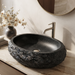 Black artificial stone oval table top wash basin 600x400x150 mm with rough natural rock textured exterior and smooth black interior, luxury designer countertop bathroom sink with modern styling and product dimensions.