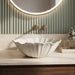 White seashell design table top wash basin 470x390x170 mm featuring elegant scalloped wavy edges, vertically ribbed shell texture and natural speckled finish, luxury designer countertop bathroom sink for modern bathrooms.