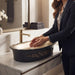 Black and champagne gold royal floral oval table top wash basin 580x370x150 mm featuring matte black exterior, metallic gold interior, antique gold ornamental scrollwork and scalloped rim for luxury bathroom countertops.