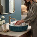 Teal green floral design round ceramic table top wash basin 400x400x120 mm featuring glossy ribbed exterior, white interior with elegant blue and olive botanical leaf patterns, luxury designer countertop bathroom sink.