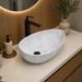 Bassino white marble pattern table top wash basin 560 × 355 × 130 mm with asymmetrical oval design for modern luxury bathroom countertops.