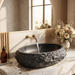 Black artificial stone oval table top wash basin 600x400x150 mm with rough natural rock textured exterior and smooth black interior, luxury designer countertop bathroom sink with modern styling and product dimensions.