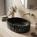 Black marble finish oval table top wash basin with white veining, sculpted vertical fluted exterior and 20 inch countertop design for modern luxury bathrooms.