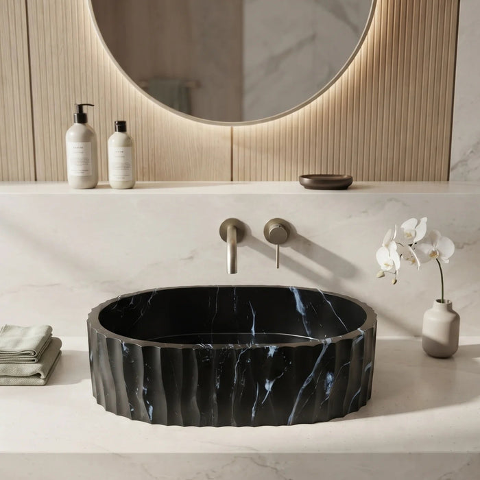 Black marble finish oval table top wash basin with white veining, sculpted vertical fluted exterior and 20 inch countertop design for modern luxury bathrooms.