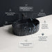 Black marble finish oval table top wash basin with white veining, sculpted vertical fluted exterior and 20 inch countertop design for modern luxury bathrooms.