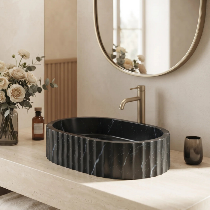 Black marble finish oval table top wash basin with white veining, sculpted vertical fluted exterior and 20 inch countertop design for modern luxury bathrooms.
