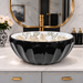 Glossy black round tabletop wash basin with a scalloped exterior and beige floral design on a white interior.