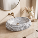 Grey oval artificial stone tabletop wash basin with a matte finish, rugged textured exterior and smooth patterned interior, measuring 500 × 400 × 150 mm.