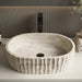 Ivory white marble finish oval table top wash basin with beige veining, vertical fluted exterior and 20 inch countertop design for modern luxury bathrooms.