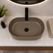 Taupe tabletop wash basin with a matte finish and wave-textured exterior, shown from multiple angles in a modern bathroom setting.