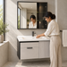 Wall-mounted bathroom vanity set with white basin, light grey cabinet, fluted door and dark-framed mirror cabinet.