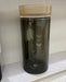 Black cylindrical container with a ribbed gold lid on a white surface.