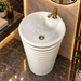 White and gold ceramic pedestal wash basin with glossy finish, sculpted cylindrical design and 440 × 440 × 820 mm size for modern luxury bathrooms.