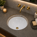 White and gold designer ceramic under counter wash basin with glossy finish, 490 × 400 × 200 mm oval undermount bathroom basin with decorative gold border pattern.